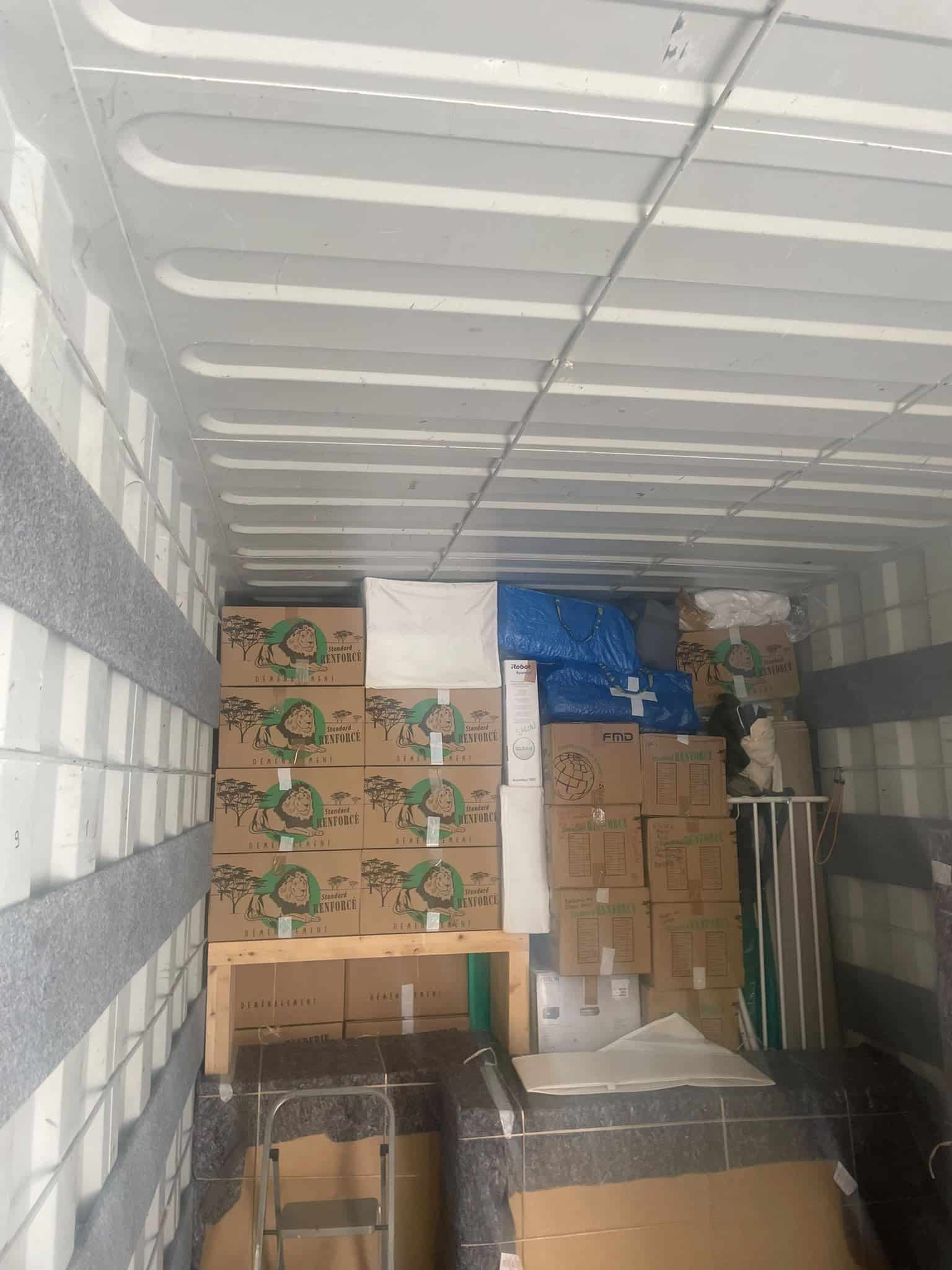 Camion de déménagement chargé de cartons Standard RENFORCÉ, sacs bleus et mobilier protégé.